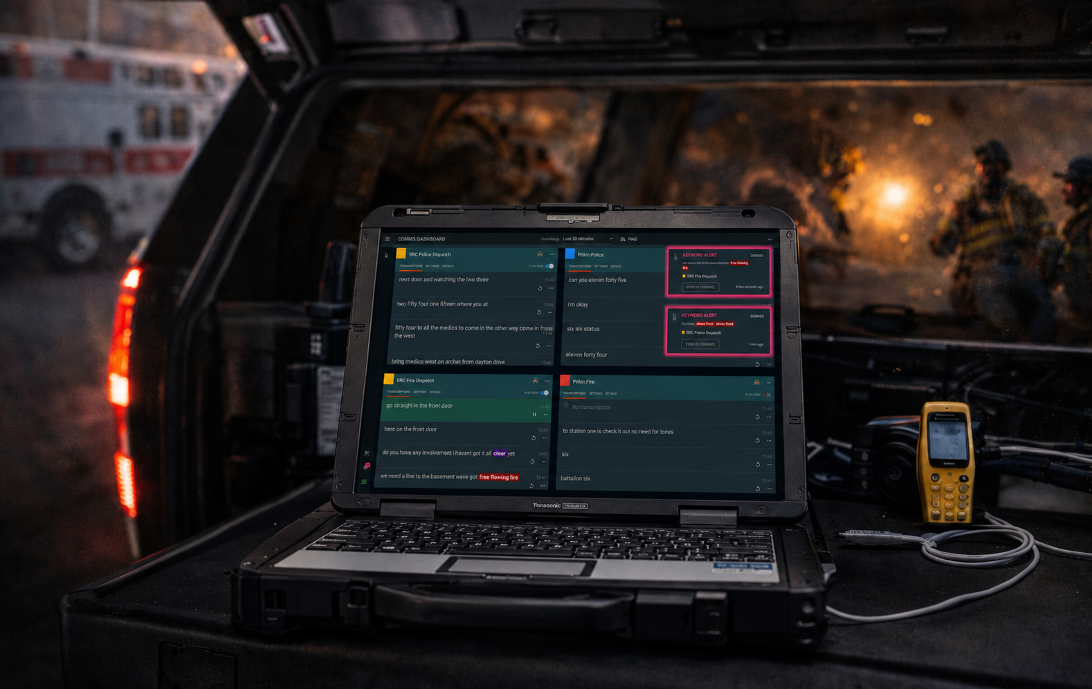 Mobile incident command workstation featuring a Panasonic Toughbook displaying real-time fire and police dispatch communications, AI radio transcription, and emergency keyword alerts while firefighters operate at a nighttime emergency scene.